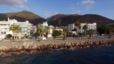Sabah Yunan boş Marina, metan. Hava video çekim. Boş bir iskele. Arka planda dağlar ve şehir evleri manzara var. Yaz Açık sabah, mavi gökyüzü bulutlu