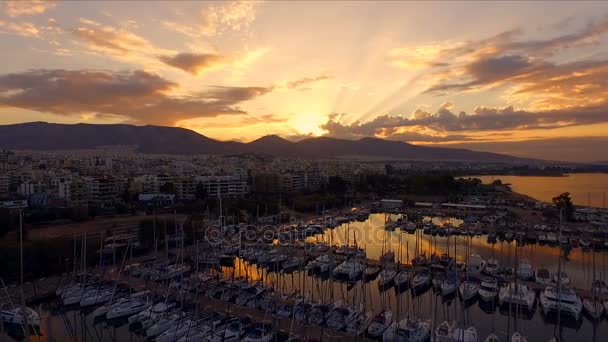 Amanecer en el puerto deportivo griego, Atenas. Grabación de video Aero. Muchos yates diferentes, catamaranes amarrados a muelles. En el fondo se encuentra el paisaje de las montañas y las casas de la ciudad. Verano claro — Vídeo de stock