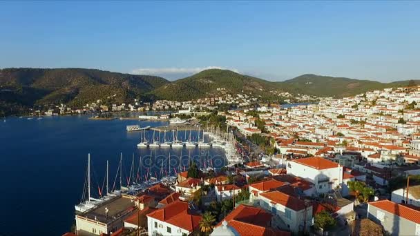 Paesaggio greco isola di Poros in mezzo al Mediterraneo, con una vista a volo d'uccello, riprese video aeree, molti ormeggiati al molo, barche a vela, catamarani, lo stretto tra le isole, un — Video Stock
