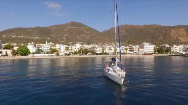 Güneşli sabah boş bir Yunan Marina, Methana, Akdeniz. Havadan video çekim, bir kuş uçuş yüksekliği. Yalnız yelkenli yat marina bırakır. Arka planda bir manzara olduğunu
