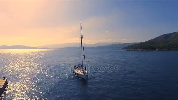 Закат в пустой греческой марине, Метана, Средиземное море. Аэровидеосъемка, в гавань заходит одинокая яхта. На заднем плане пейзаж с моря, ясное голубое небо, солнечный — стоковое видео