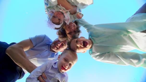 青い空を背景に、下から撮影が行われます、全体の家族を採用し、円、お母さん、お父さん、2 人の男の子、3 歳と 7 歳と女の赤ちゃんに集まった。彼らは笑顔します。 — ストック動画