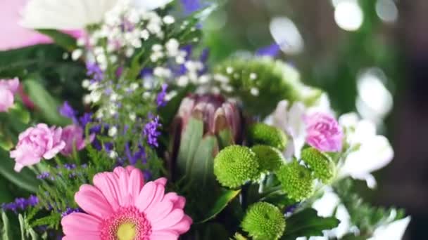 Nahaufnahme, Blumenstrauß in den Lichtstrahlen, Rotation, die florale Komposition besteht aus Chrysanthemen-Anastase, Zigeunerblume, Solidago, Barbatus, Protea, Nelke, Gerbera, — Stockvideo