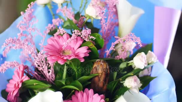 Primer plano, Ramo de flores en los rayos de luz, rotación, la composición floral consta de gerberas rosadas, Protea, calla, Rose yana cremosa, solidago Russus . — Vídeo de stock