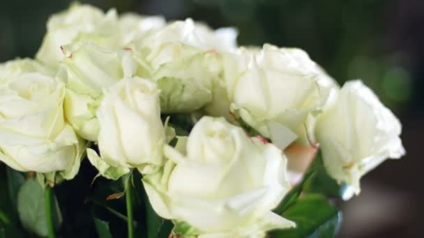 Крупным планом, букет цветов в лучах света, вращение, цветочная композиция состоит из белых роз. на заднем плане много зелени. божественная красота — стоковое видео