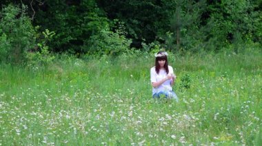 Yaz ortasında bir orman, genç bir kadın, bir esmer bir papatya çim chamomiles çelenk örgüleri