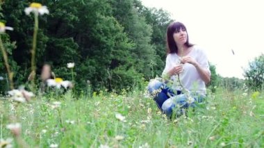 Yaz ortasında bir orman, genç bir kadın, bir esmer bir papatya çim chamomiles çelenk örgüleri