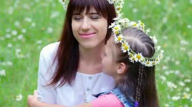 Summer, orman, genç bir kadın, bir esmer bir papatya çim ortasında ve yedi, anne ve kızı bir kız örgü chamomiles, çelenk gülüyor, çelenk üzerinde çalışıyor