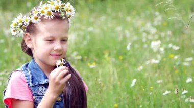 Bir papatya'nın bahçesinde, tatlı bir kız chamomiles, daisy, bakar bir çelenk içinde yaprakları keser, o burnunu çekmek ve gülümsüyor