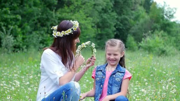森、若い女、ブルネット、カモミールの芝生に囲まれた夏し、7、母と娘の女の子、鎮静の花輪を織りは、笑って、花輪にしようとして — ストック動画