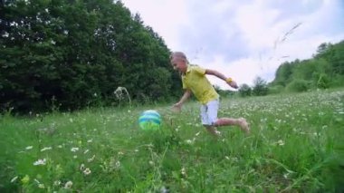 Bir papatya Tarih çayır, bir orman, bir çocuk, bir çocuk, yakınındaki top oynar, atar, peşinden çalışır. Eğleniyor. Summer, açık havada, ormanda. Çocuklu tatil