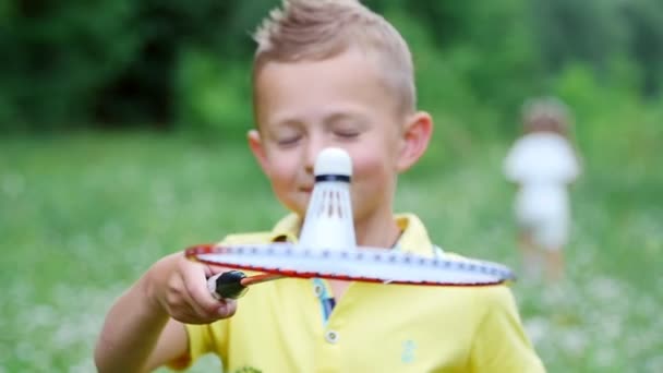 Крупним планом, дитина, хлопчик, тримає човник на бадмінтоні, кидає його і б'є — стокове відео