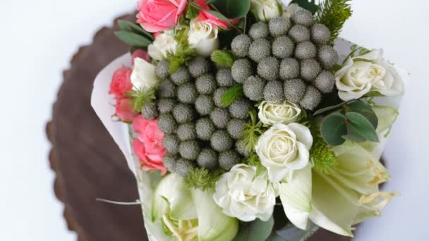 Bovenaanzicht, close-up van een boeket van bloemen, rotatie, bestaat uit eucalyptus, cineraria, Rose Room genade, Rose barbados, Eustoma, solidago, Santini, feverweed, Brunia groen. — Stockvideo