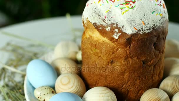 Zbliżenie, obrót, skład Wielkanoc Świąteczna w promienie światła, na słomie, na duży talerz, ozdobione kolorowych jaj, istnieje duże pasque z ciasta. — Wideo stockowe