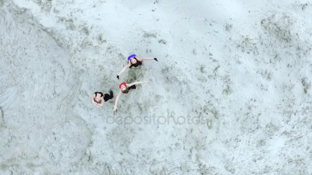 Три молодые атлетичные женщины делают упражнения на растяжку, разминку, на песчаной вершине карьера, на пляже. Рассвет. Аэровидеосъемка. вид сверху . — стоковое видео