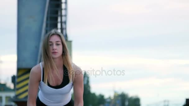 Portret, jonge, atletische, vrouw, voert kracht oefeningen met behulp van een dikke, sportieve touw. Bij dageraad, langs de zand pier van de vrachthaven, in het zonlicht — Stockvideo