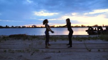 Güzel, ince genç kadın fitness içinde nişanlandık, güç egzersizleri gerçekleştirin. Şafakta güneşin karşı çekim video kargo bağlantı noktası, kum iskele boyunca. Güneş doğarken,