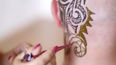 Yakın çekim, yürütme bir usta, bir sanatçı Mehdi, dövme, resmini kına Beyaz Cilt derisi üzerinde kel bir beyaz adam. Siyah, koyu kahverengi soyut süsler