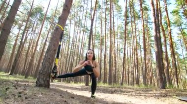 Güzel, atletik, seksi genç kadın, Koç, eğitmen, egzersiz, fitness trx sistemi, Trx askı kayışları ile egzersizleri yapıyor gerçekleştirir. Çam ormanı içinde yaz, güneş ışınları.