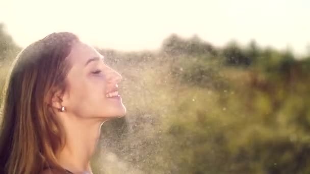 Retrato de uma jovem loira sexy e bonita, sob uma leve chuva de verão, nos raios de sol, em um prado verde. A menina sorri, sua pele brilha, irradia saúde. Imagem de felicidade — Vídeo de Stock