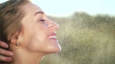 Güzel bir genç sarışın kız, hafif yaz yağmur, güneş ışınları, bir yeşil çayır altında portresi. Kız gülümsüyor, kendini narin, güzel beyaz cilt üzerinde vuruş