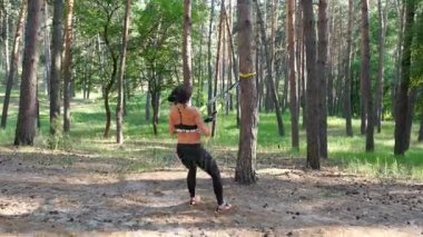Güzel, atletik, seksi genç kadın, Koç, eğitmen, egzersiz, fitness trx sistemi, Trx askı kayışları ile egzersizleri yapıyor gerçekleştirir. Çam ormanı içinde yaz, güneş ışınları.