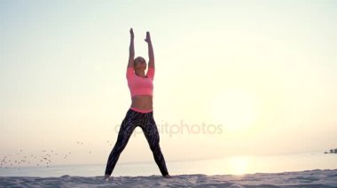 Sağlıklı, genç güzel kadın meditasyon, germe, pratik yoga deniz plajda güneş doğarken, denge ve koordinasyon, derin Kas tonusu için egzersizler yapar.