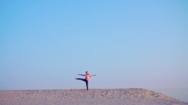 Sağlıklı, genç güzel kadın meditasyon, germe, pratik yoga deniz plajda güneş doğarken, denge ve koordinasyon, derin Kas tonusu için egzersizler yapar.