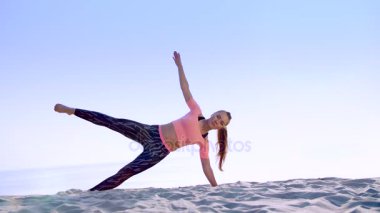 Sağlıklı, genç güzel kadın oblik karın basın kaslar, sahilde, güneş doğarken yapıyor egzersizleri denge ve koordinasyon, derin Kas tonusu için yapar.