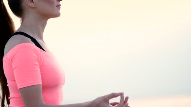 Gesunde, junge schöne Frau meditiert, praktiziert Yoga im Sand, am Strand, am Meer, Fluss, im Morgengrauen, bei Sonnenaufgang, Nahaufnahme — Stockvideo