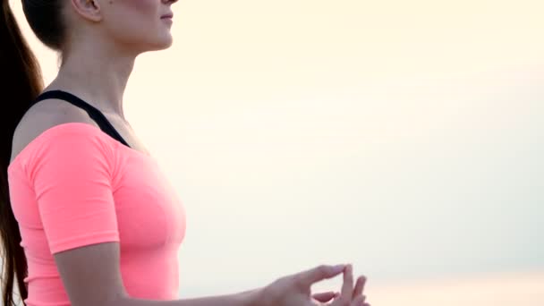 Jeune belle femme en bonne santé méditant, pratiquant le yoga dans le sable, sur la plage, au bord de la mer, rivière, à l'aube, au lever du soleil, gros plan — Video