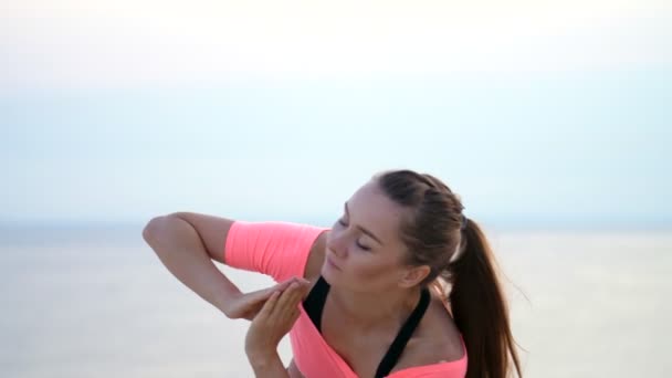 Mujer sana, joven y hermosa meditando, practicando yoga en la playa del mar, al amanecer, hace ejercicios para el equilibrio y la coordinación, tono muscular profundo. de cerca — Vídeos de Stock