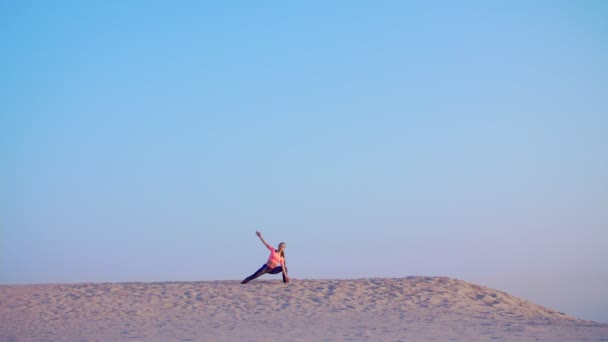 Mulher bonita saudável, jovem meditando, alongamento, praticando ioga na praia do mar, ao nascer do sol, faz exercícios de equilíbrio e coordenação, tônus muscular profundo . — Vídeo de Stock