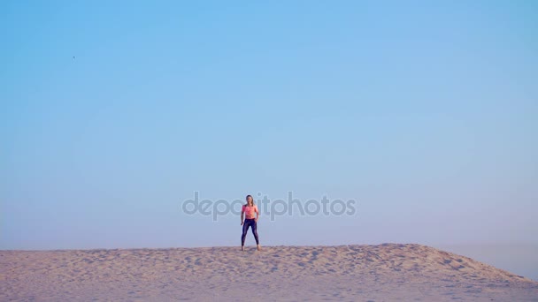 Mulher bonita saudável, jovem meditando, alongamento, praticando ioga na praia do mar, ao nascer do sol, faz exercícios de equilíbrio e coordenação, tônus muscular profundo . — Vídeo de Stock