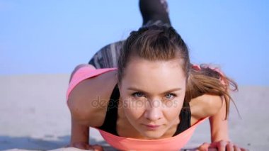 Sağlıklı, genç güzel kadının yapması, push-up, sahilde, güneş doğarken gerçekleştirir, denge ve koordinasyon, derin Kas tonusu için egzersizler yapar. Yakın çekim, portre