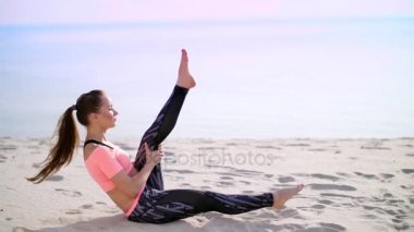 Sağlıklı, genç güzel kadın egzersiz kasları basına alır vücut, bacak, pompalar için sahilde kum güneş doğarken yatan basın gerçekleştirir