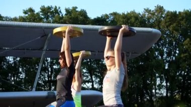 güneş gözlüğü, tayt, ağırlığı, egzersizleri yapıyor gün batımı, atletik, genç kadınlarda, ağır ağırlık plaka, terkedilmiş bir Havaalanı, eski bir uçak arka planı üzerinde,