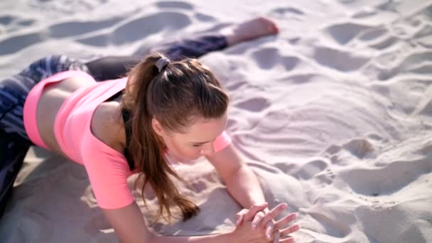 Mujer sana, joven y hermosa estirándose, practicando yoga en la playa, al amanecer, hace ejercicios para el equilibrio y la coordinación, tono muscular profundo. relajación de los músculos, mente — Vídeos de Stock