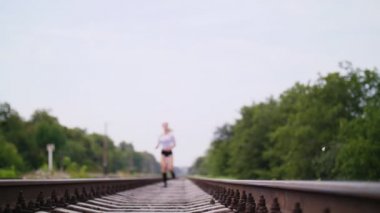 Güzel seksi atletik genç sarışın bir kadın üst ve çalışan, şort, jogging, durur, aittir, ağır nefes alır, yorgun, kameraya benziyor. Demiryoluna, yaz.
