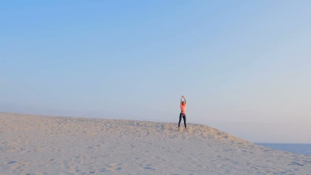 Junge schöne Frau springt, macht Übungen im Gleichgewicht und Koordination, auf dem Sand, an einem einsamen Strand, im Sommer. Blick von oben, Aero-Videoaufzeichnung. — Stockvideo