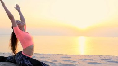 Sağlıklı, genç güzel kadın meditasyon, germe, pratik yoga deniz plajda güneş doğarken, denge ve koordinasyon, derin Kas tonusu için egzersizler yapar