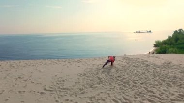 Sağlıklı, genç güzel kadın meditasyon güneş gözlüğü, germe, pratik yoga deniz plajda güneş doğarken, denge, koordinasyon, derin kas tonu egzersizleri yapar.