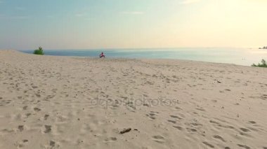 Sağlıklı, genç güzel kadın meditasyon güneş gözlüğü, germe, pratik yoga deniz plajda güneş doğarken, denge, koordinasyon, derin kas tonu egzersizleri yapar.