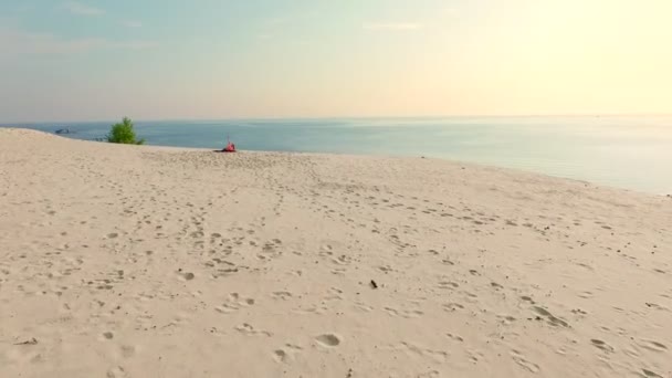 Friska, unga vackra kvinnan i solglasögon mediterar, stretching, öva yoga på en strand vid havet, vid soluppgången, gör övningar för balans, samordning, djupa muskeltonus. — Stockvideo