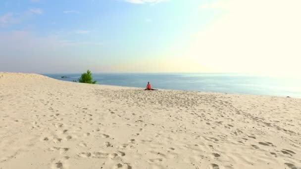 Gezonde, jonge mooie vrouw in zonnebril mediteren, uitrekken, het beoefenen van yoga op het strand zee bij zonsopgang, Oefeningen voor balans, coördinatie, diepe spierspanning maakt. — Stockvideo