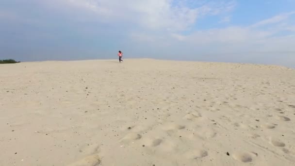 Zdrowy, młody sportowe piękna kobieta w okulary biegnie wzdłuż piasku, na plaży, w lecie, ku słońcu, o wschodzie słońca. Filmowanie z powietrza — Wideo stockowe
