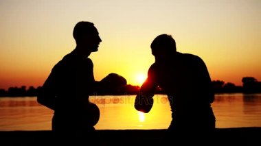 İki karanlık erkek resimler, gündoğumu, boks, fikir tartışması içinde mücadele teknikleri grev bir çift içinde eğitim ışığa karşı. Kumsalda, yaz aylarında suya yakın kargo bağlantı noktası