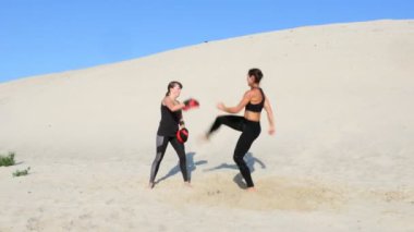 Siyah fitness uygun bir çift nişanlandık iki atletik, genç kadınlarda iş başladı mavi gökyüzü karşı bir ıssız plajda yaz, sıcak güneşin altında.