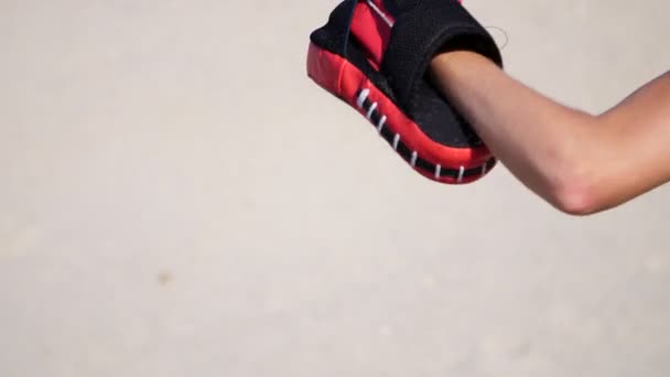 Close-up, female leg, a work in pairs, kicking a special glove. On a deserted beach, in summer, under a hot sun. Slow motion — Stock Video