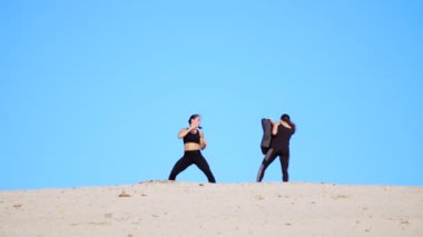 Siyah fitness uygun bir çift nişanlandık iki atletik, genç kadınlarda başladı yerine getirmek, ıssız plajda, mavi gökyüzü karşı yaz, sıcak güneşin altında dövüşmek tren. Ağır çekim